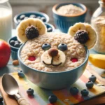 A cozy kitchen scene with a child-friendly breakfast setup. A teddy bear-shaped bowl sits atop a wooden table, filled with creamy porridge. The porridge is adorned with slices of banana for ears, a blueberry for a nose, and a strawberry for a mouth, resembling a cute teddy bear face. Next to the bowl, a spoon rests invitingly, ready for a playful breakfast experience. In the background, a kettle steams gently on the stove, adding to the comforting atmosphere.